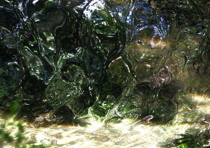 Close-up of water flowing over green glass stones